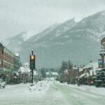 Snow-covered street in Banff, Alberta with mountain backdrop and stoplights